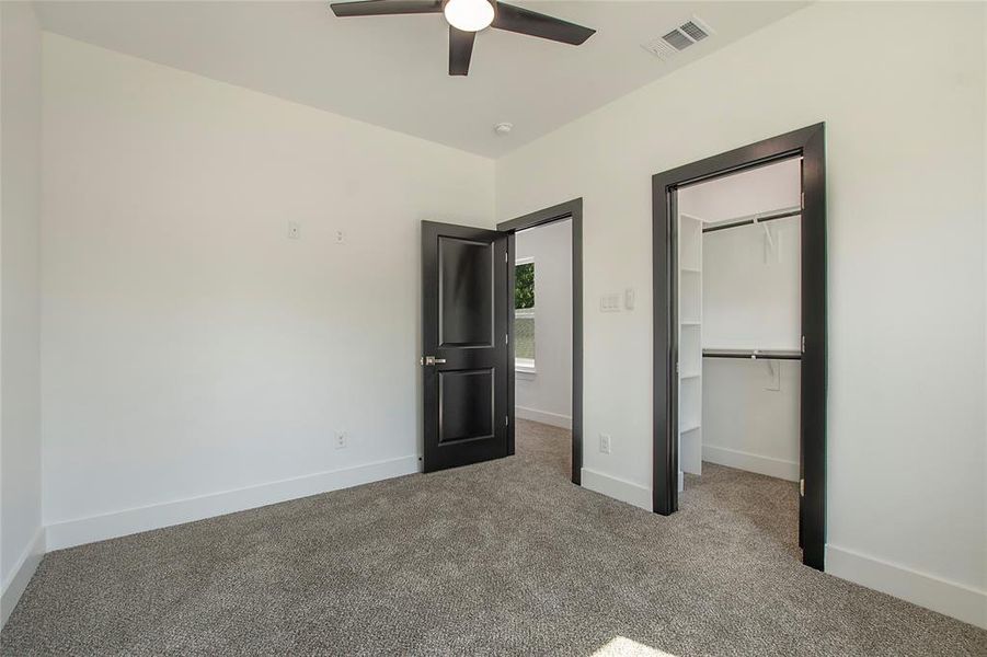 Unfurnished bedroom featuring carpet, a closet, a spacious closet, and ceiling fan