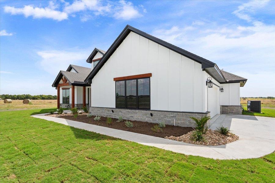 This newly constructed home presents striking curb appeal with modern farmhouse aesthetics and a manicured landscape.