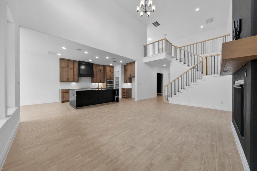 Expansive open-concept kitchen and living area with soaring ceilings, abundant natural light, and elegant wood-look flooring.