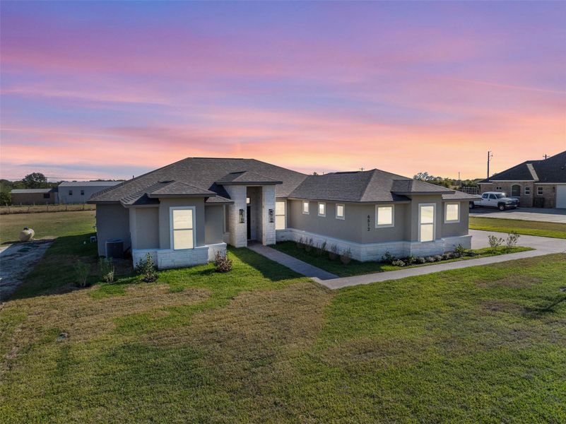 Prairie-style house featuring a front lawn, stone siding, roof with shingles, and stucco siding