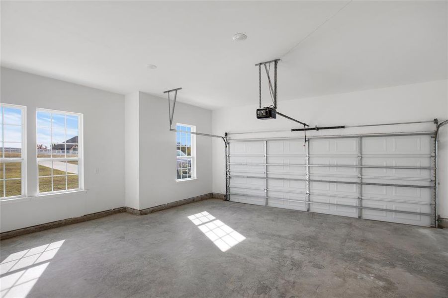 Garage with baseboards and a garage door opener Garage with baseboards and a garage door opener
