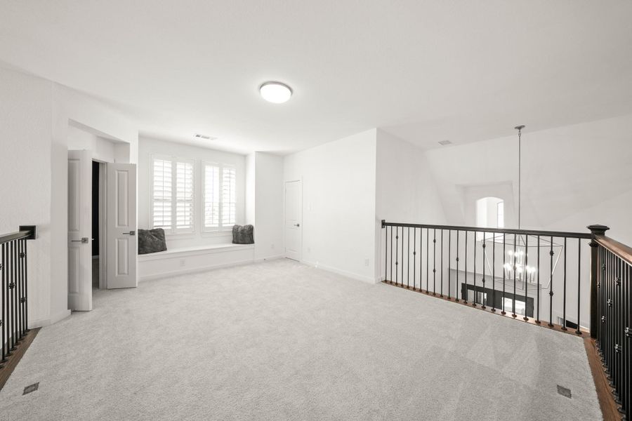 Wood stair treads lead to the second floor game room flanked by wrought iron spindles and matching wood handrails.