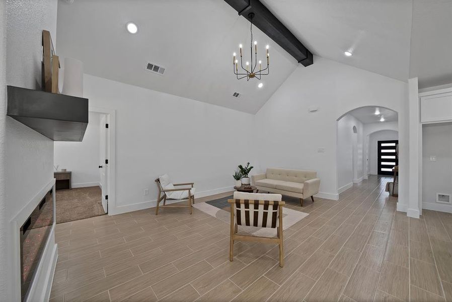 Living area with arched walkways, beamed ceiling, high vaulted ceiling, a chandelier, and tiled floors