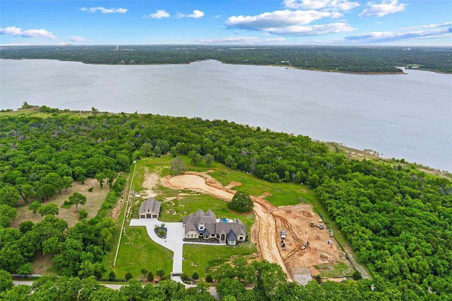 Expansive estate featuring a large main residence, detached garage, and a broad body of water bordering the property Expansive estate featuring a large main residence, detached garage, and a broad body of water bordering the property