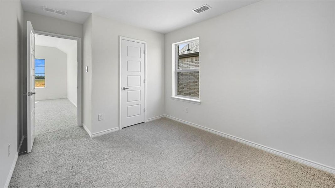 Unfurnished bedroom featuring light carpet and multiple windows