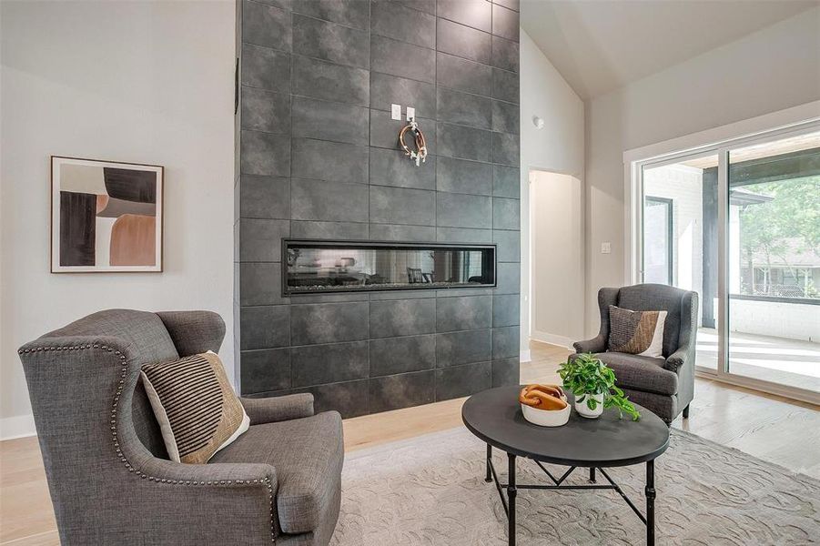 Living area featuring high vaulted ceiling, baseboards, wood finished floors, and a multi sided fireplace Living area featuring high vaulted ceiling, baseboards, wood finished floors, and a multi sided fireplace