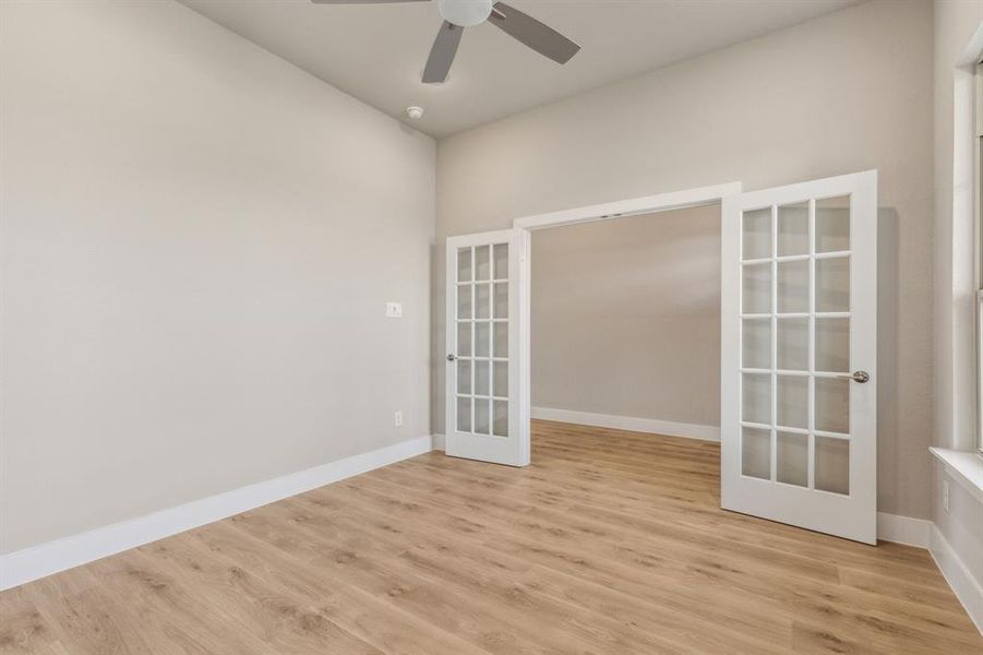 Spare room featuring ceiling fan, french doors, and light wood-type flooring