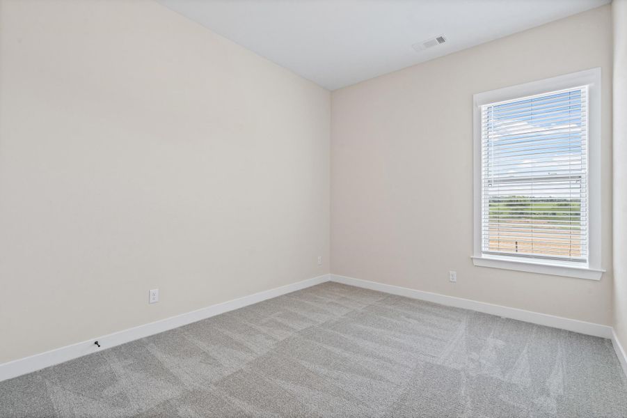 Room featuring neutral wall paint, gray patterned carpeting, a white-framed window with blinds, and white baseboards Room featuring neutral wall paint, gray patterned carpeting, a white-framed window with blinds, and white baseboards