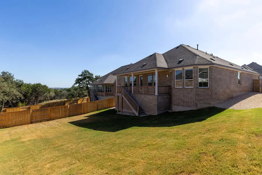 Rear view of property with stairs, a fenced backyard, roof with shingles, brick siding, and a patio area