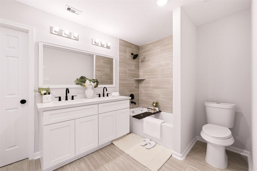 Primary bathroom. Spa-like retreat with a quartz-topped custom vanity with dual sinks. Beautiful tiles, elegant fixtures, and high-arc faucets. Indulge and relax in the upgraded bathtub after a long day of hard work.