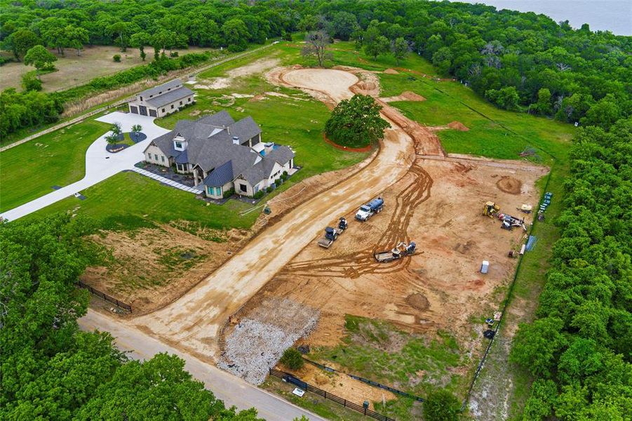 Expansive property featuring a stone and stucco residence with a dark roof, an additional detached building, a long paved driveway, and significant undeveloped land Expansive property featuring a stone and stucco residence with a dark roof, an additional detached building, a long paved driveway, and significant undeveloped land