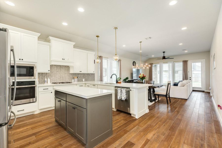 Open floor plan with island, storage, stainless steel appliances, and beautiful wooden floors create an elegant space. Open floor plan with island, storage, stainless steel appliances, and beautiful wooden floors create an elegant space.