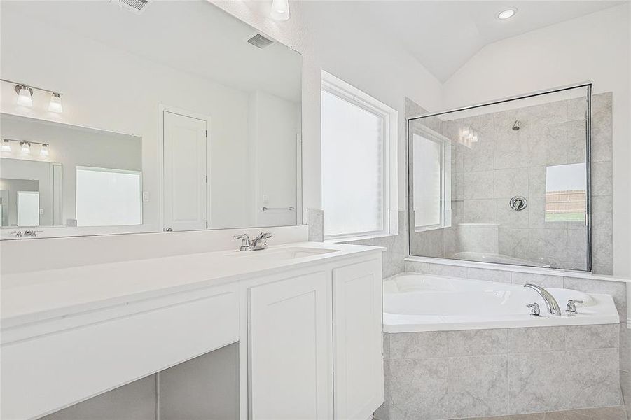 Bathroom featuring vanity, lofted ceiling, and shower with separate bathtub