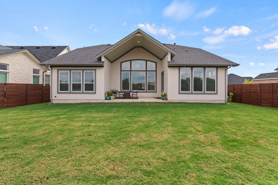 Back of house with roof with shingles, a fenced backyard, stucco siding, and a patio area Back of house with roof with shingles, a fenced backyard, stucco siding, and a patio area
