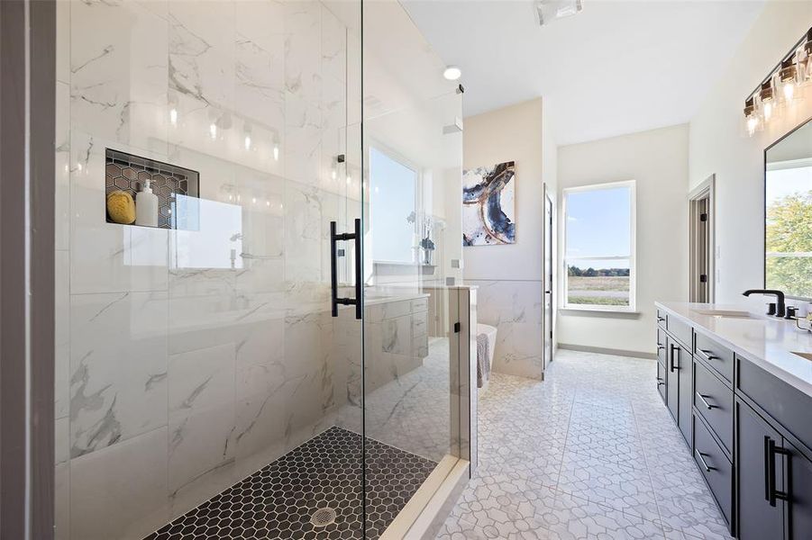 Bathroom featuring vanity, a shower with shower door, and a wealth of natural light