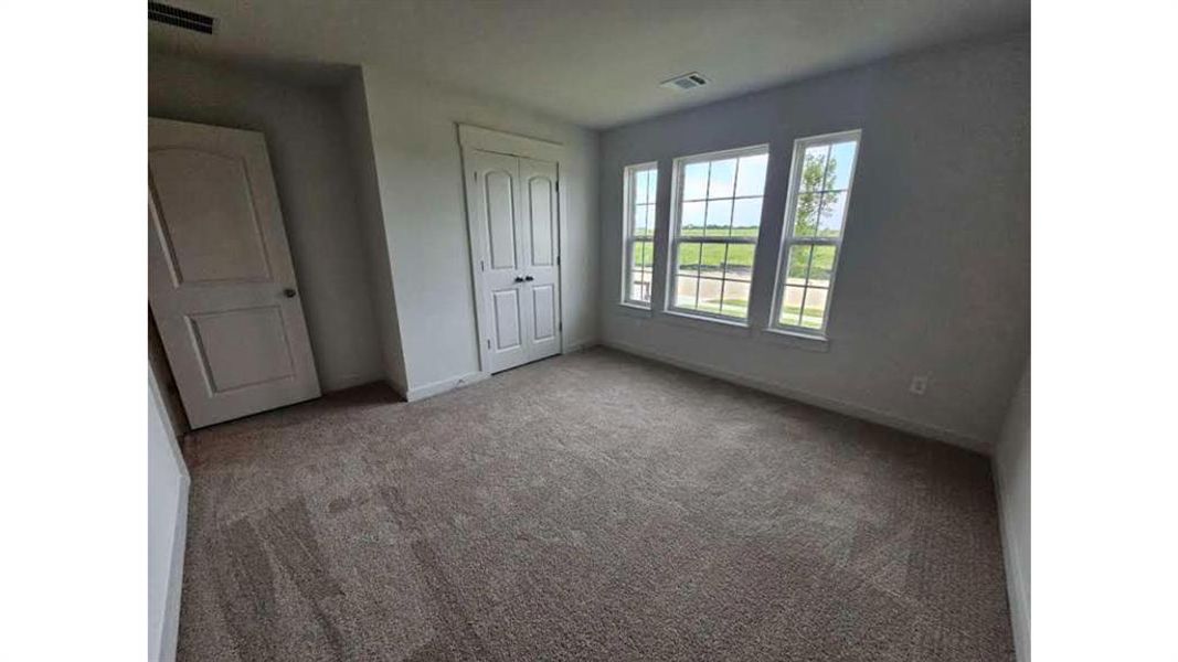 Carpeted interior room featuring multiple windows with grid detailing, two paneled doors, and white baseboards