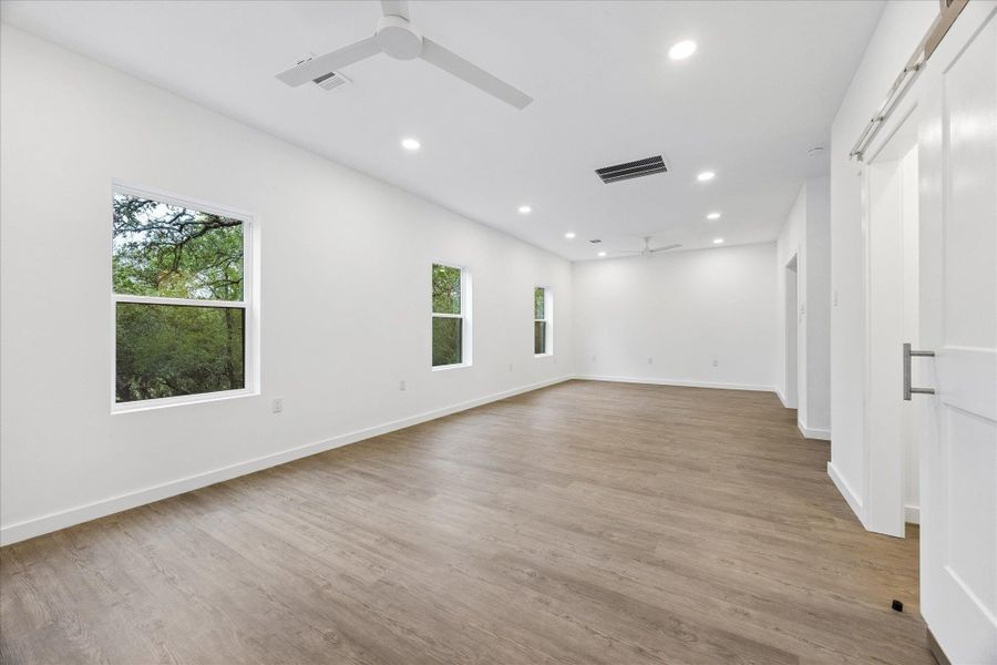 A spacious, open-plan room with recessed lighting and beautiful wood-look flooring.