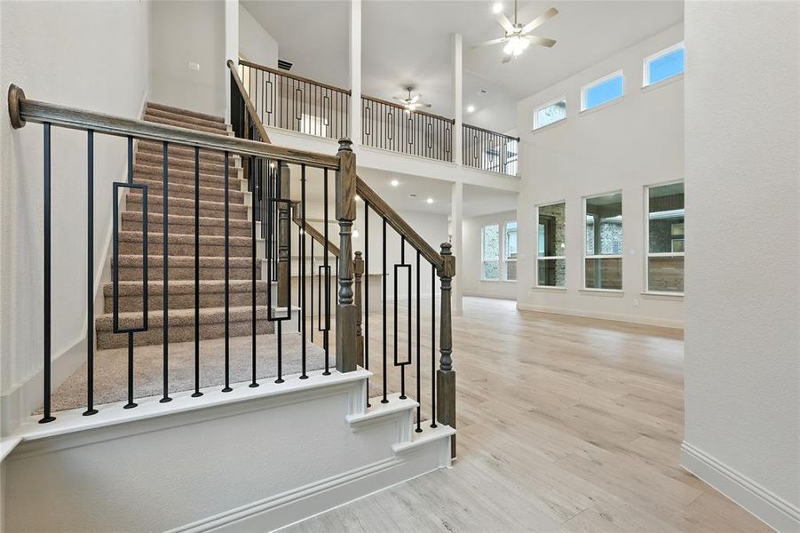 Stairway with wood finished floors, plenty of natural light, a ceiling fan, and a towering ceiling