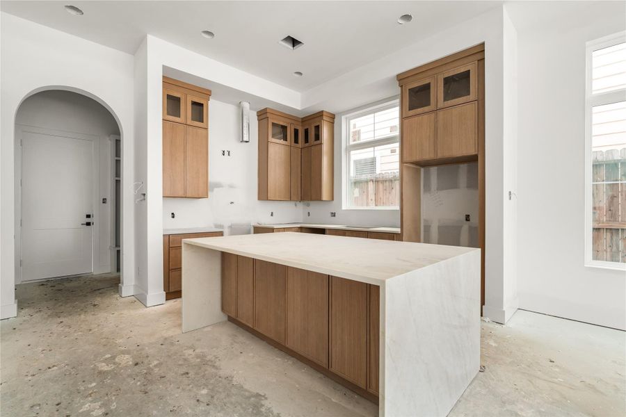 This home's kitchen comes with Taj Mahal counters, oversized island with storage on both sides, white oak slim shaker cabinetry, luxury Bosch appliances, Delta champagne bronze fixtures, and white oak wood flooring.