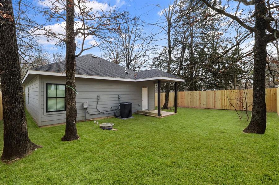 Back of property with central AC and a lawn