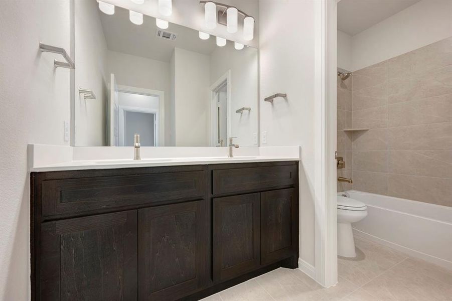 Full bath with double vanity, shower / bathtub combination, and light tile patterned floors