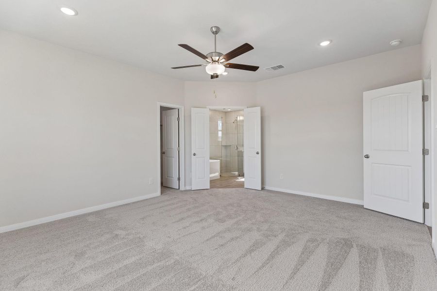Plush carpeting and recessed lighting create a comfortable, quiet atmosphere in this main bedroom.