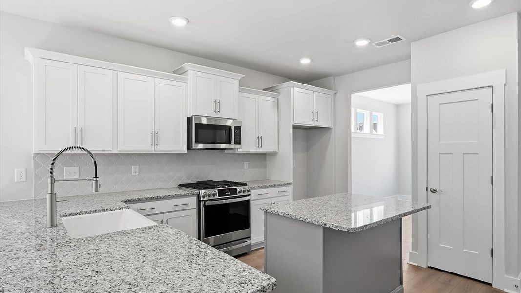 Superior craftsmanship shines in this modern kitchen with a space-saving island and open flow by DRB Homes