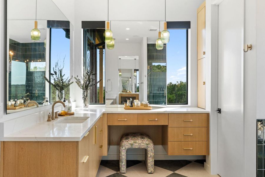 Spacious vanity area featuring light wood cabinetry, white countertop, integrated sink, and a makeup vanity with storage drawers