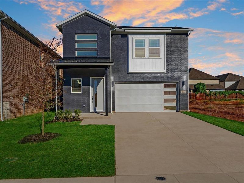 Contemporary house with brick siding, driveway, a standing seam roof, an attached garage, and a metal roof