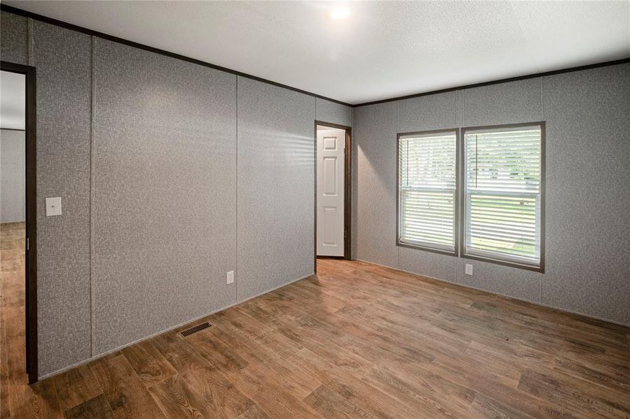 Empty room featuring wood finished floors and a decorative wall