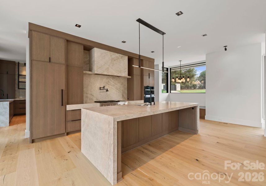 Kitchen featuring a waterfall island, custom cabinetry, and high-end appliances. Kitchen featuring a waterfall island, custom cabinetry, and high-end appliances.
