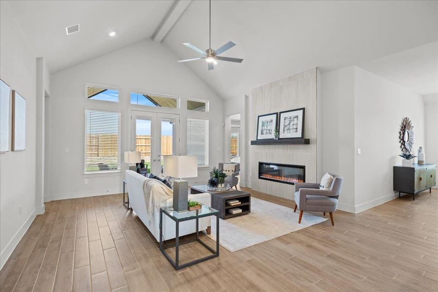 Living area with light wood-style flooring, a large fireplace, ceiling fan, and french doors