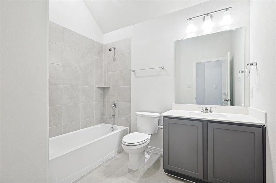 Bathroom featuring shower / washtub combination, vanity, light tile patterned floors, and vaulted ceiling Bathroom featuring shower / washtub combination, vanity, light tile patterned floors, and vaulted ceiling