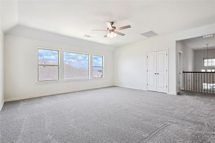 Empty room featuring carpet floors, lofted ceiling, and ceiling fan