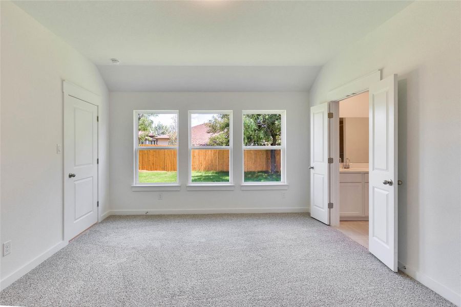 Empty room featuring vaulted ceiling and light colored carpet Empty room featuring vaulted ceiling and light colored carpet