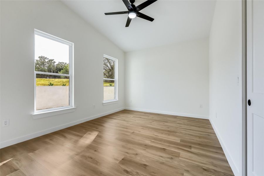 Unfurnished room featuring lofted ceiling, ceiling fan, and light wood-style floors Unfurnished room featuring lofted ceiling, ceiling fan, and light wood-style floors