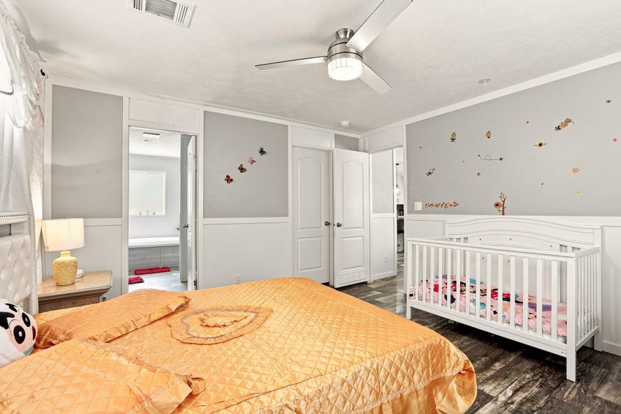 Smooth wood-look flooring and custom wall paneling create a cohesive feel in this comfortable bedroom.
