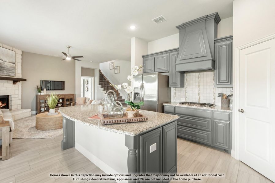 Kitchen with gray cabinets, granite island, custom range hood, and open view to living room with fireplace