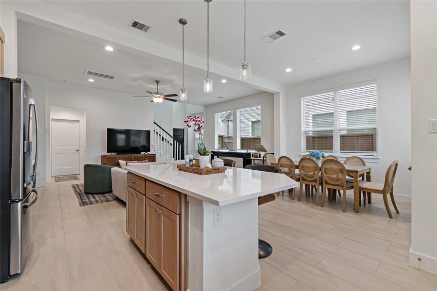 Bright and open-concept living space features a modern kitchen with an island, a cozy living area with a ceiling fan, and a spacious dining area with large windows for natural light. Bright and open-concept living space features a modern kitchen with an island, a cozy living area with a ceiling fan, and a spacious dining area with large windows for natural light.