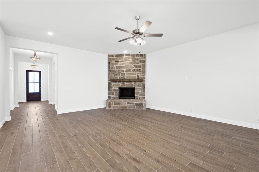 Unfurnished living room featuring recessed lighting, a stone fireplace, a ceiling fan, and dark wood-style flooring Unfurnished living room featuring recessed lighting, a stone fireplace, a ceiling fan, and dark wood-style flooring