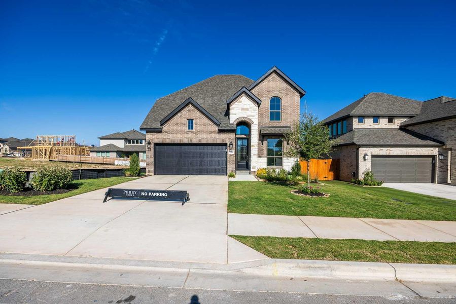 French country inspired facade featuring brick siding, concrete driveway, and stone siding French country inspired facade featuring brick siding, concrete driveway, and stone siding