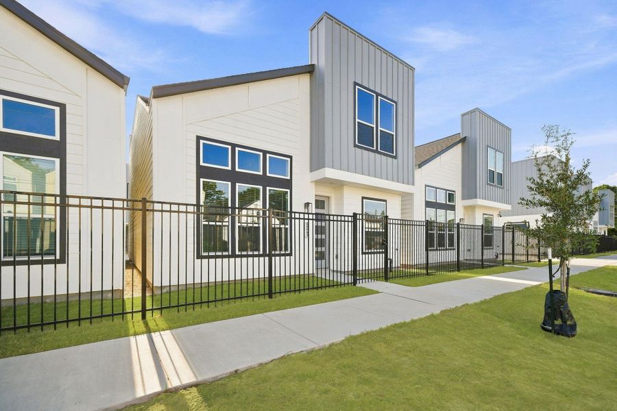 Street-level view showcasing the modern architecture, fenced front yards, sidewalks, and cohesive contemporary design throughout the community. Street-level view showcasing the modern architecture, fenced front yards, sidewalks, and cohesive contemporary design throughout the community.