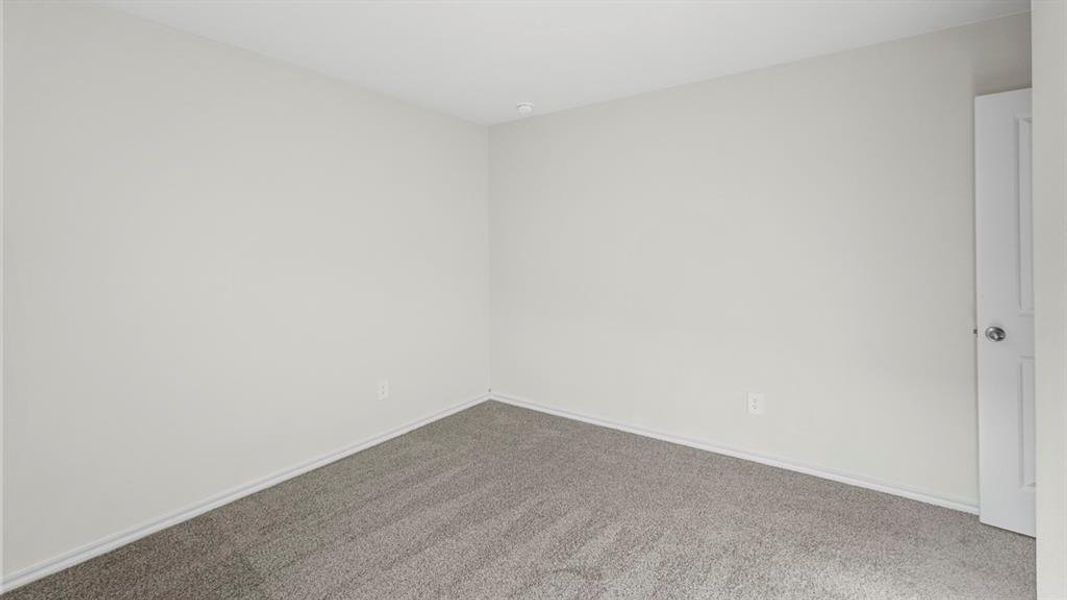 Carpeted spare room featuring baseboards