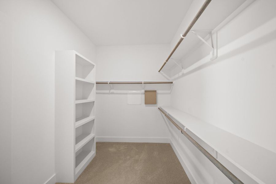 Another view of the walk-in closet highlights its depth and ample storage space along with a built-in shoe shelf for easy organization. Another view of the walk-in closet highlights its depth and ample storage space along with a built-in shoe shelf for easy organization.