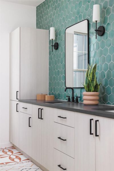 Primary bathroom with dual vanities, plenty of storage, and beautiful natural light. Floor and wall tiles are all handmade from Clay Imports.