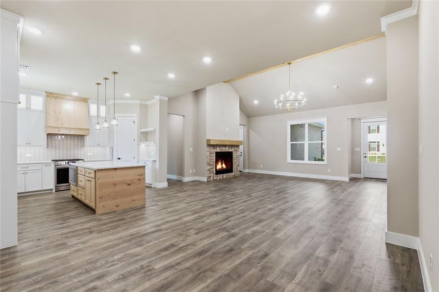Spacious open-concept living area featuring wood-finish flooring and vaulted ceilings