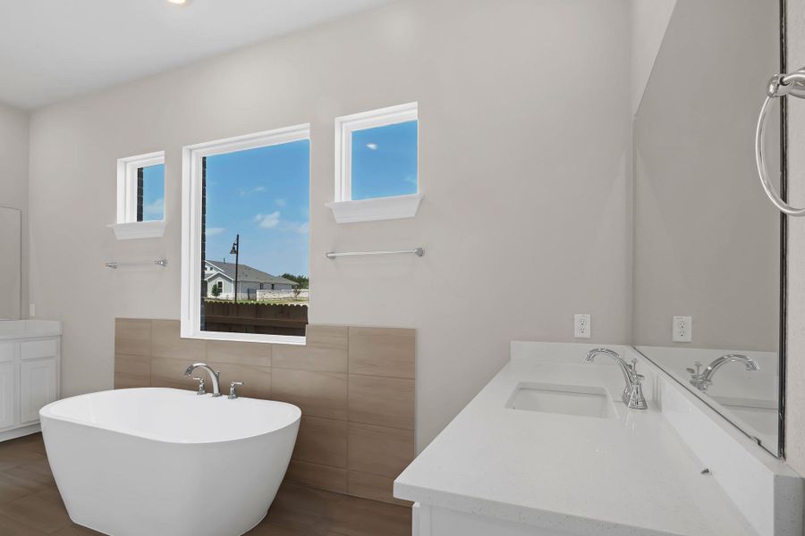 Full bathroom featuring double vanity, a freestanding tub, tile walls, and a sink Full bathroom featuring double vanity, a freestanding tub, tile walls, and a sink