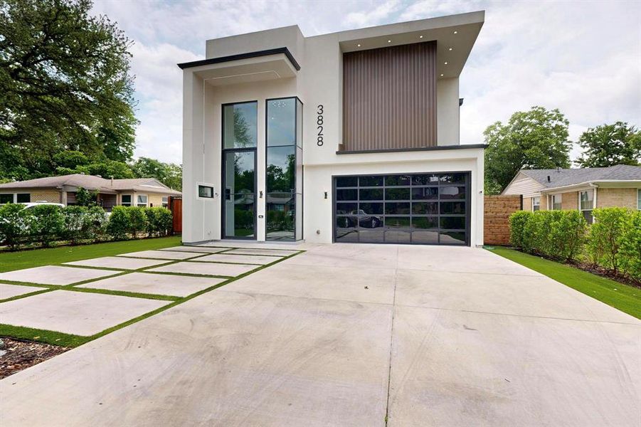 Modern home featuring driveway, stucco siding, and a garage Modern home featuring driveway, stucco siding, and a garage