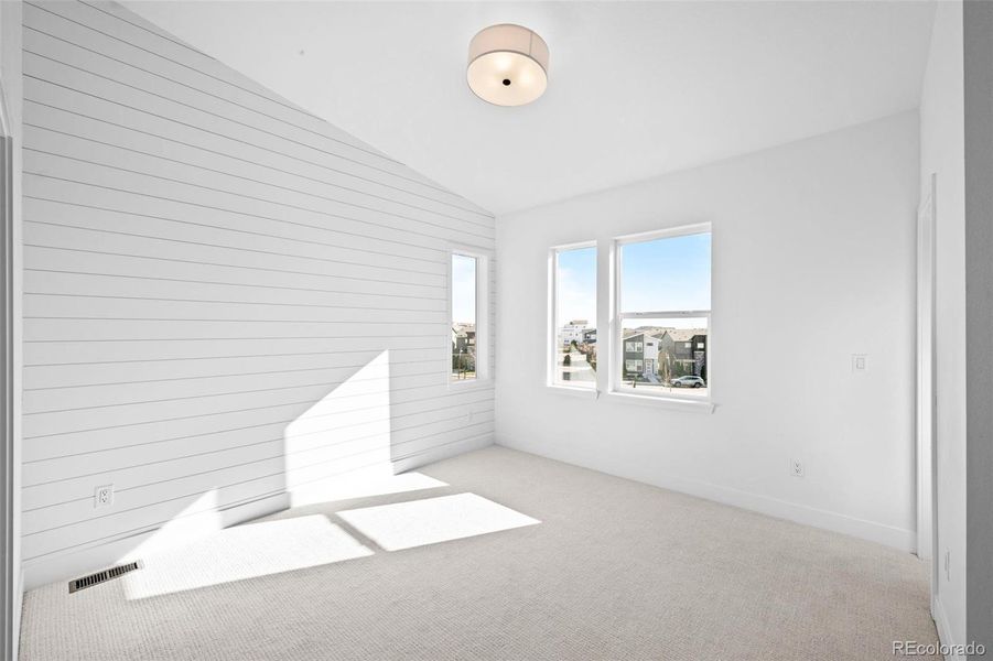 Primary bedroom with vaulted ceilings & upgraded lighting.