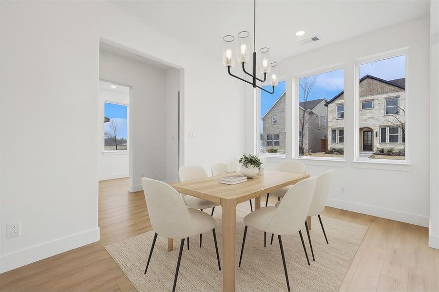 Dining room with a chandelier, light wood finished floors, and healthy amount of natural light virtually staged
